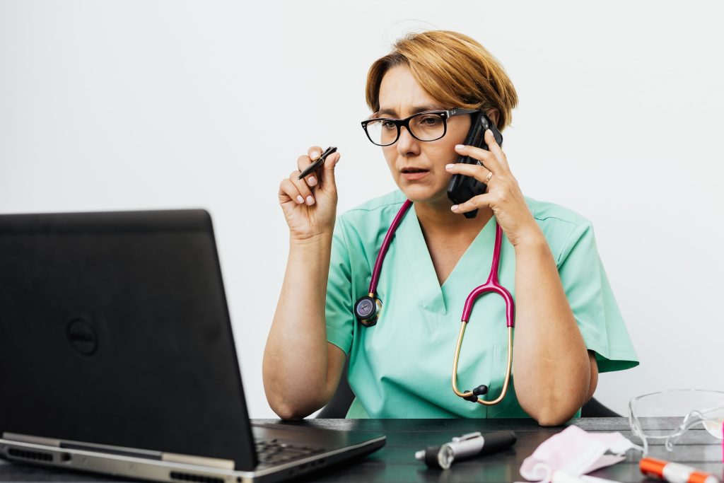 Doctor speaking on the phone while reviewing patient information on a laptop during a doctor-on-call consultation in Dubai.