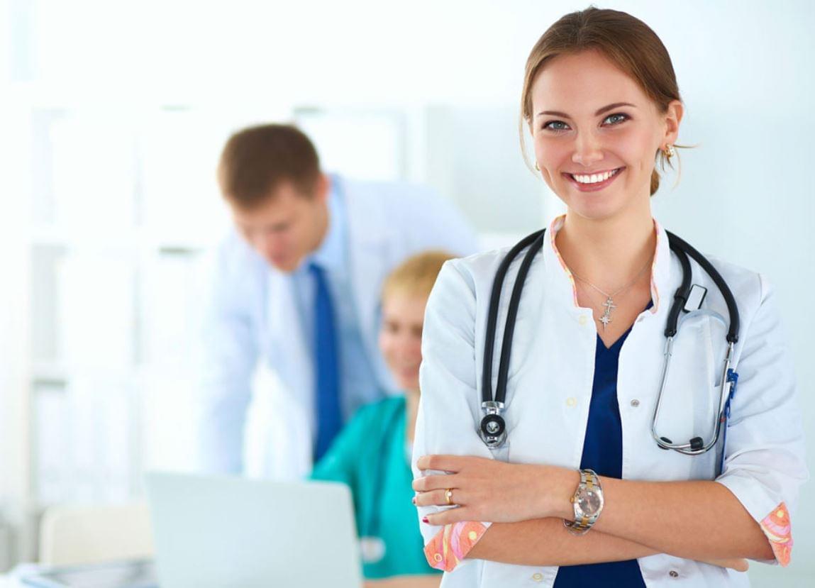 Smiling doctor with stethoscope standing confidently in a modern clinic, representing doctor on call in Dubai.